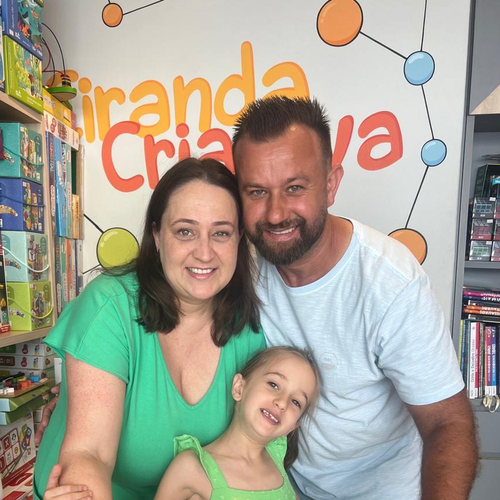 Josiane, a Amábile e a família na frente da parede da Ciranda Criativa, dentro da loja